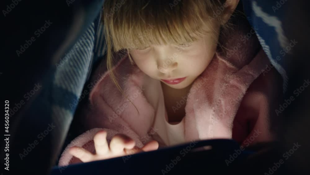 cute little girl using digital tablet computer under blanket enjoying learning on touchscreen technology playing games having fun at bedtime cute little girl using digital tablet computer under blanket enjoying learning on touchscreen technology playing games having fun at bedtime