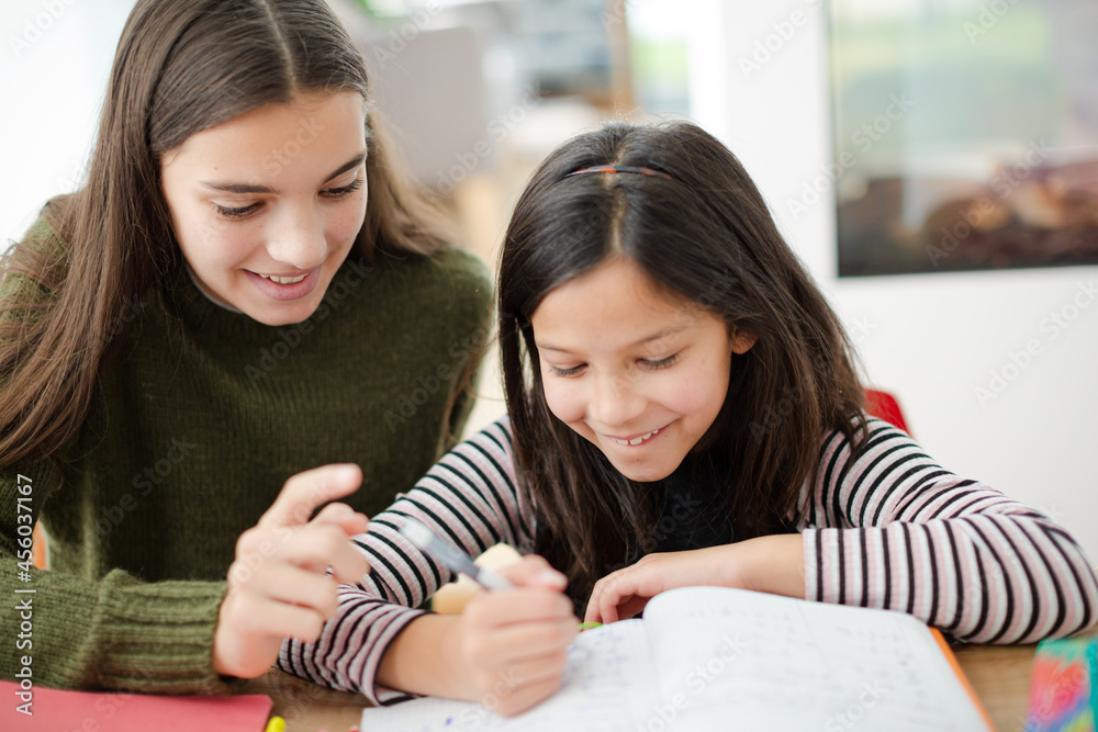 Girl helping young sister with homework Girl helping young sister with homework