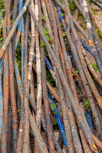 A pile of rusty steel pipes on the ground. Rusty mounting pipes at a construction site.