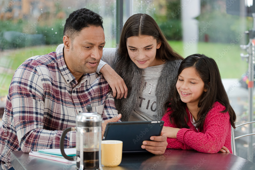 Father and daughters using digital tablet in morning kitchen Father and daughters using digital tablet in morning kitchen