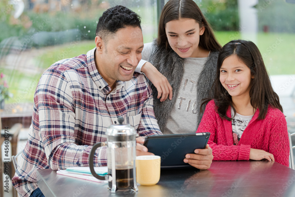 Father and daughters using digital tablet in morning kitchen Father and daughters using digital tablet in morning kitchen
