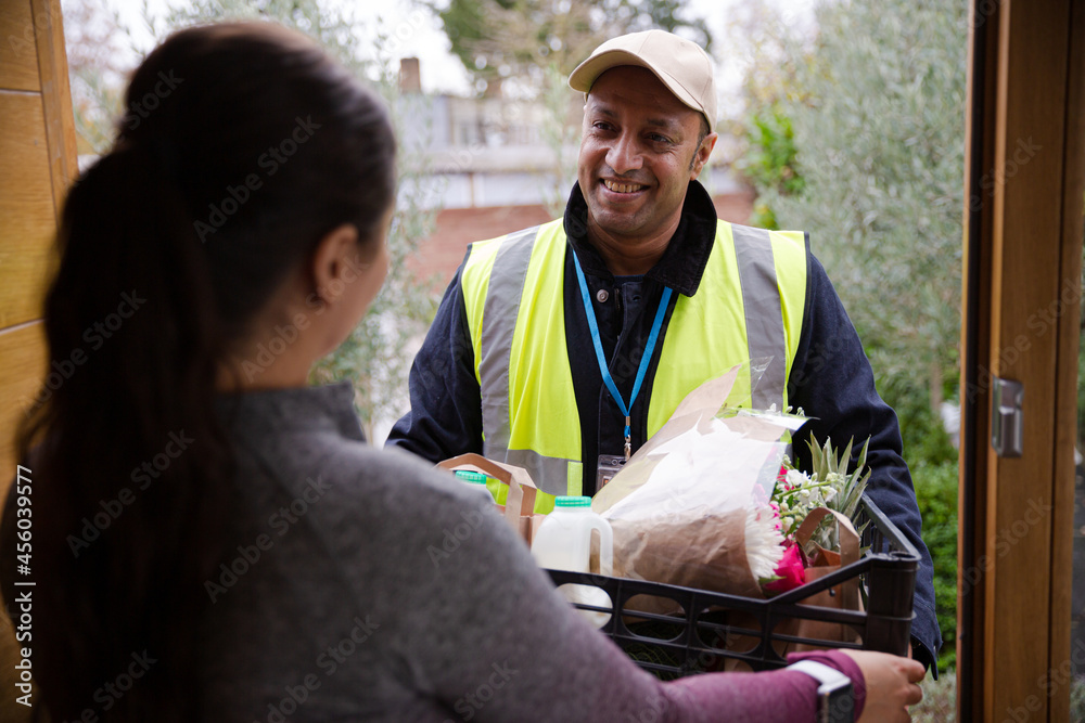 Woman greeting food deliveryman at front door Woman greeting food deliveryman at front door
