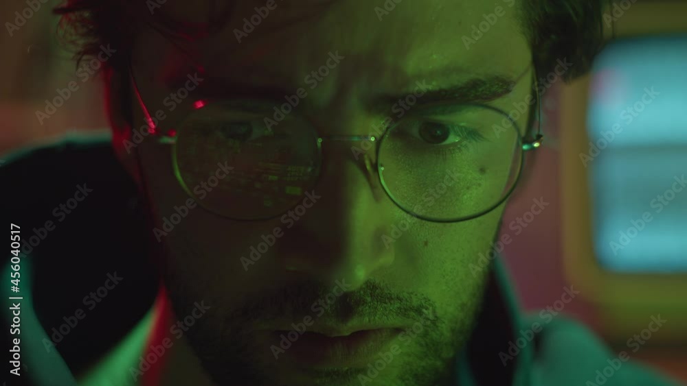 Close-up of hacker face, stealing information, preparing to break password. Young man criminal wearing circle glasses, typing on keyboard. Professional hacker attack. Close-up of hacker face, stealing information, preparing to break password. Young man criminal wearing circle glasses, typing on keyboard. Professional hacker attack.