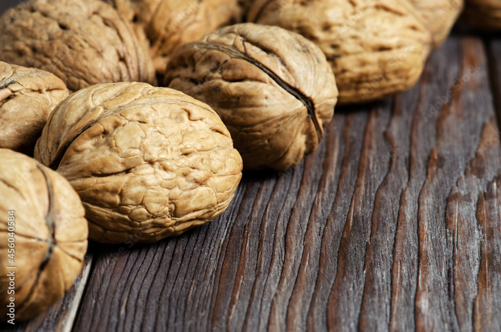 Walnuts on a dark brown wooden background. Close up. Selective focus, side view. Copy space.