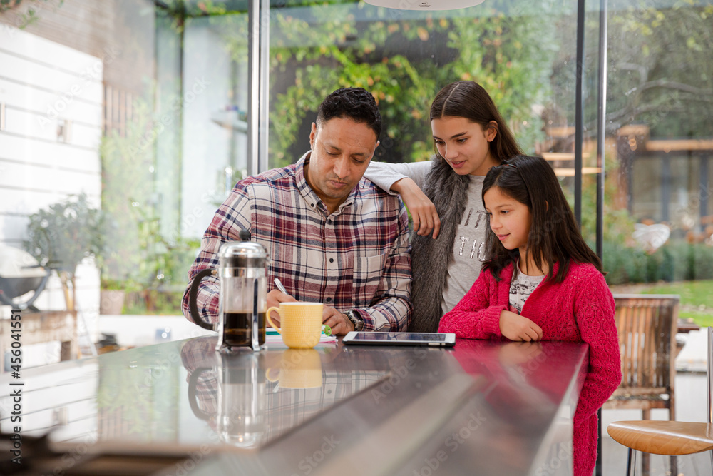 Family using digital tablet at kitchen table Family using digital tablet at kitchen table