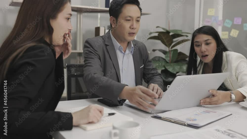 Motivated middle-aged Asian businessman and two young businesswomen happily exchanged ideas for business plans, enjoying working together at the office. Motivated middle-aged Asian businessman and two young businesswomen happily exchanged ideas for business plans, enjoying working together at the office.