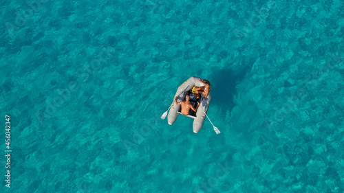 Aerial drone photo of small inflatable rib boat operated by young couple in turquoise clear water sea