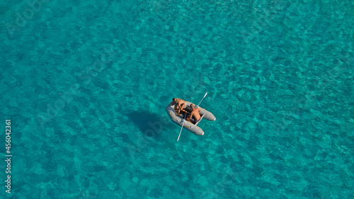 Aerial drone photo of small inflatable rib boat operated by young couple in turquoise clear water sea © aerial-drone