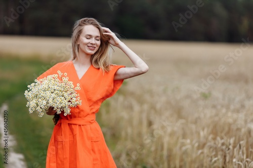 A beautiful young woman is walking in a wheat field