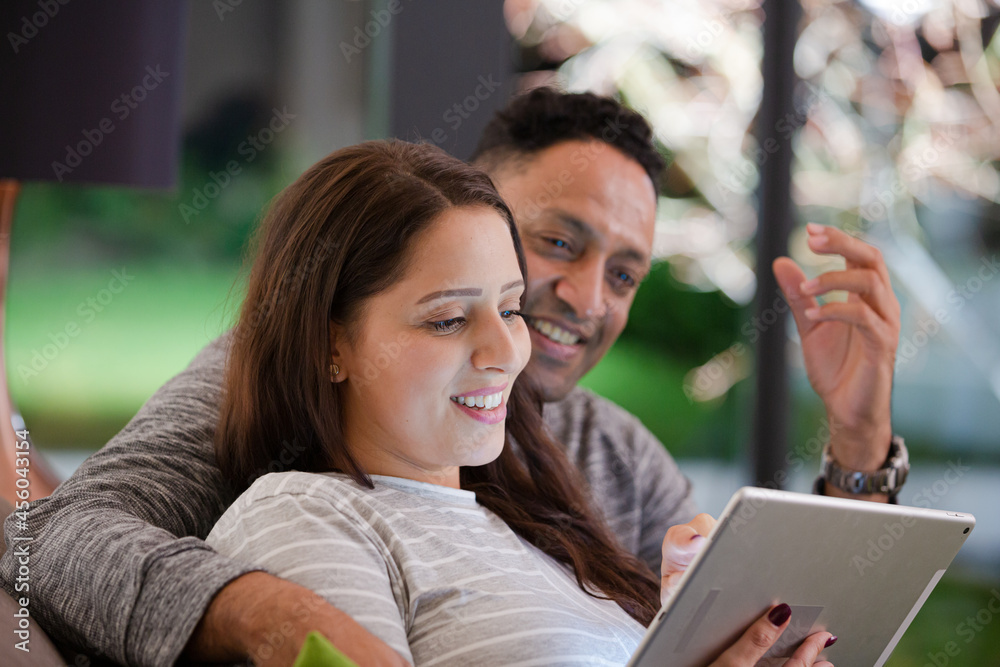 Couple relaxing, using digital tablet on living room sofa Couple relaxing, using digital tablet on living room sofa