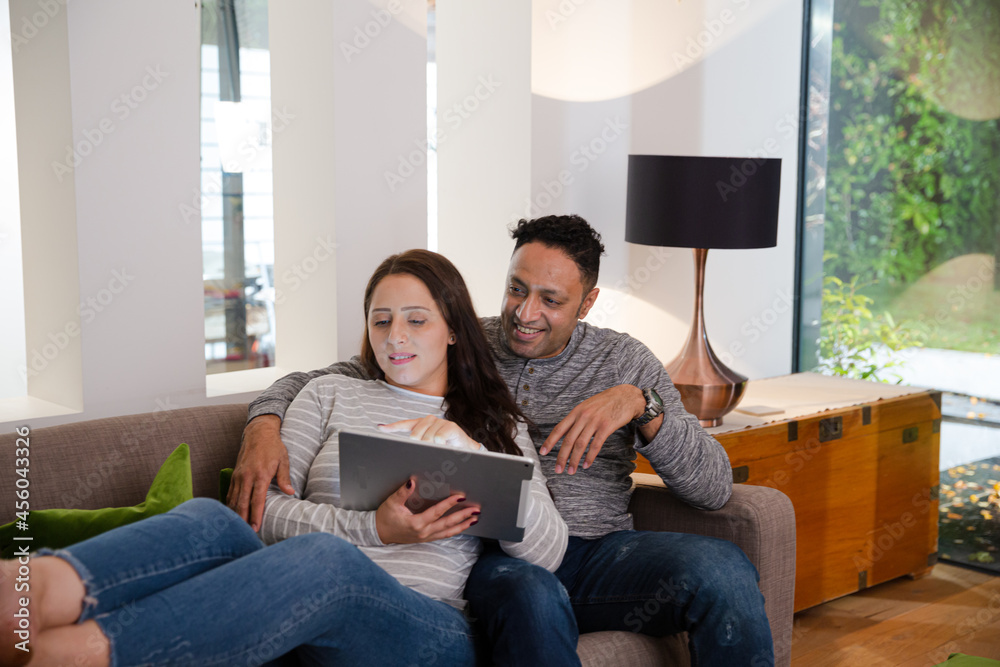Couple relaxing, using digital tablet on living room sofa Couple relaxing, using digital tablet on living room sofa