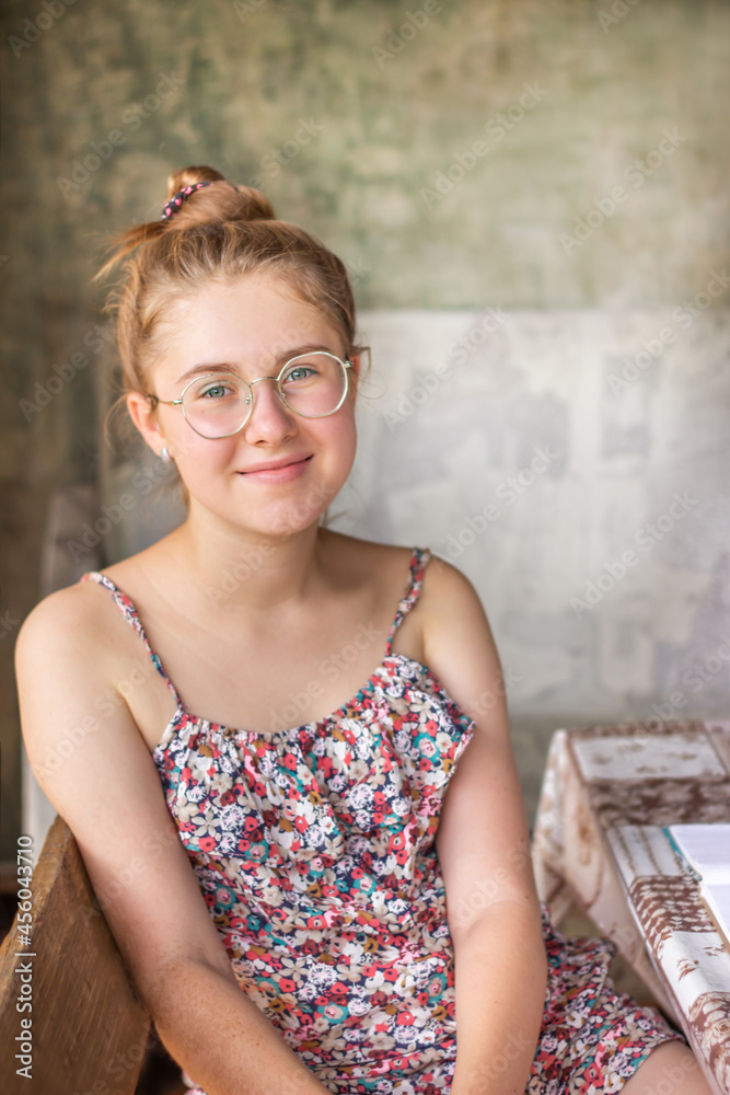 Portrait of a healthy young woman with glasses at a table on a gray background Portrait of a healthy young woman with glasses at a table on a gray background