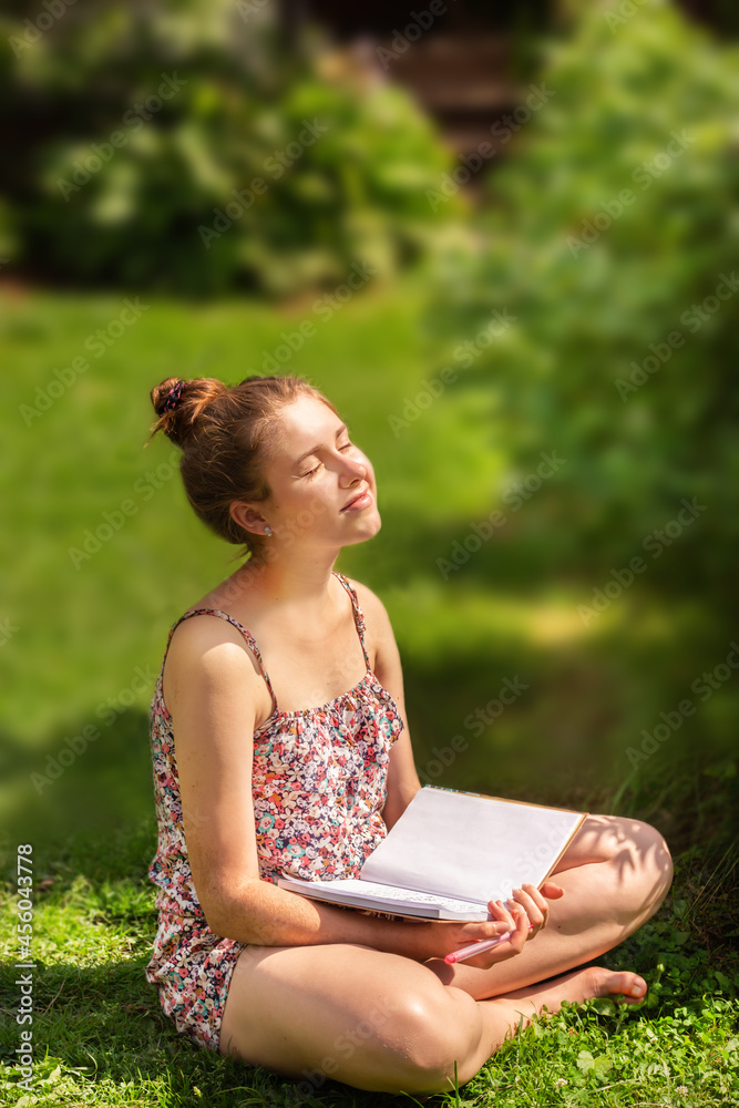 Portrait of a healthy young woman with glasses with a book on the grass Portrait of a healthy young woman with glasses with a book on the grass