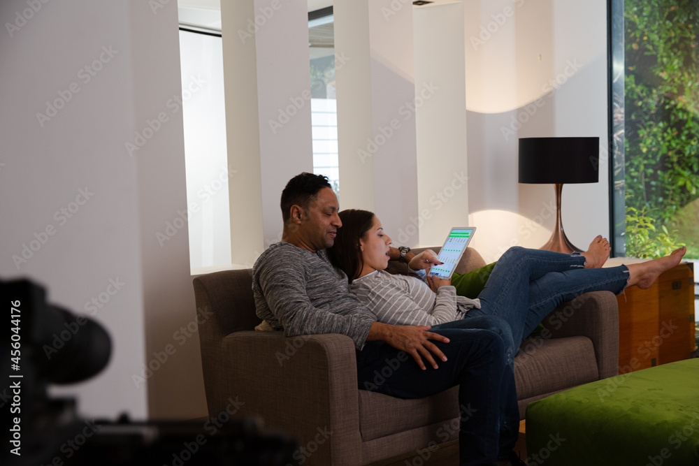 Affectionate couple relaxing, ordering groceries from digital tablet on living room sofa Affectionate couple relaxing, ordering groceries from digital tablet on living room sofa