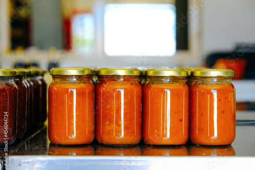 Closeup of fresh quince marmalade in jars on table at factory photo