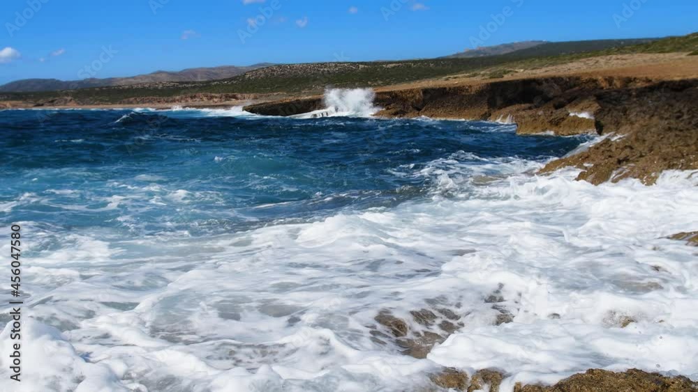 Sea blue water and rocks, Sunny daytime seascape, Devastating and spectacular, ocean waves crash on the rocks of the coast creating an explosion of water Sea blue water and rocks, Sunny daytime seascape, Devastating and spectacular, ocean waves crash on the rocks of the coast creating an explosion of water