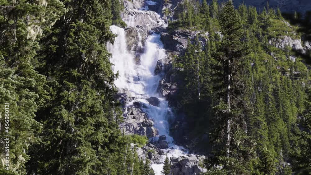 Waterfall cascading down a rocky mountain cliff in Canadian Nature Landscape. Sunny Summer Evening. Wedgemount Lake Hike in Whistler, British Columbia, Canada. Slow Motion Waterfall cascading down a rocky mountain cliff in Canadian Nature Landscape. Sunny Summer Evening. Wedgemount Lake Hike in Whistler, British Columbia, Canada. Slow Motion