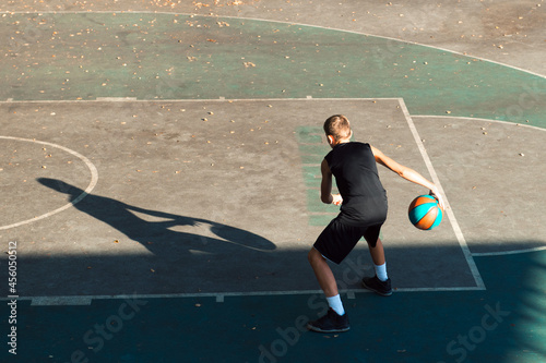 Teenager boy basketball player dribbling on sports ground photo