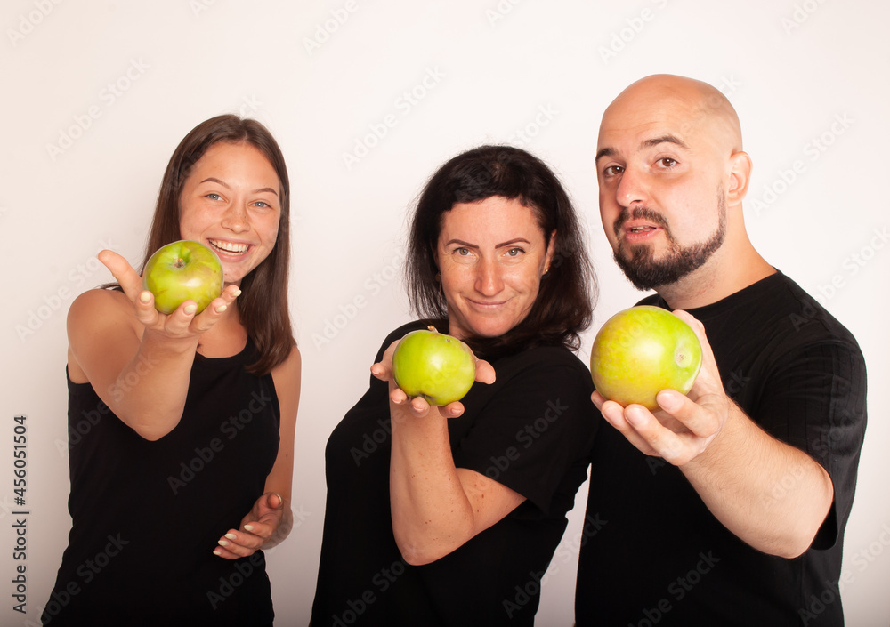 a family with apples in their hands portray funny theatergoers vegetarians for a healthy image of life against meat. The concept of weight loss a family with apples in their hands portray funny theatergoers vegetarians for a healthy image of life against meat. The concept of weight loss