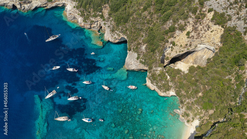 Aerial drone photo of sail boats anchored in tropical Caribbean island paradise bay with white rock caves and turquoise clear sea