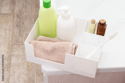 Plastic organizer for bathroom accessories. Сontainer box with towel, shampoo and toothbrush