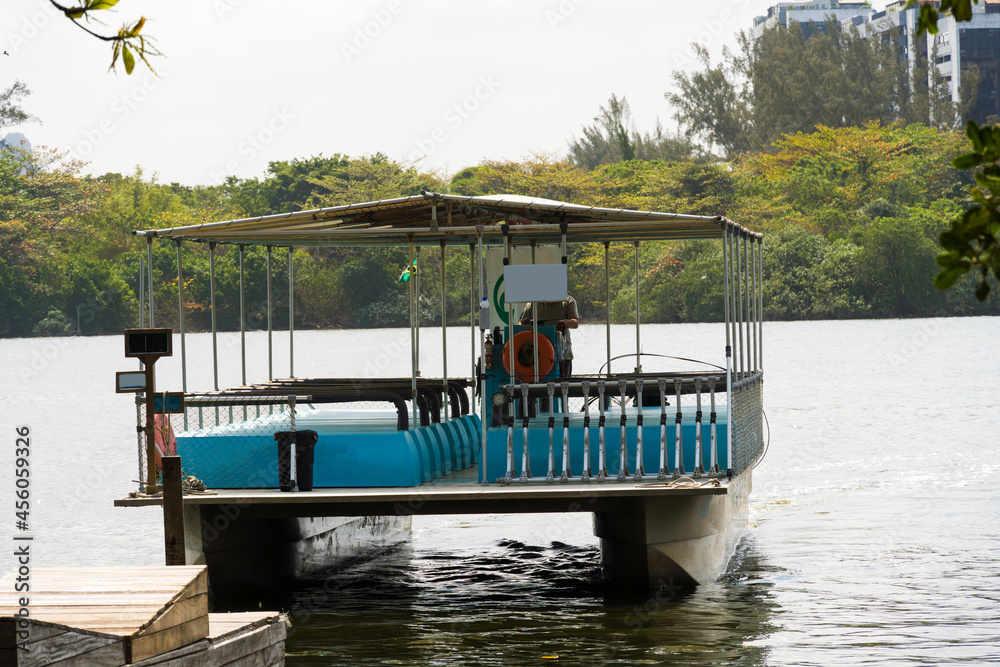 Fototapeta premium View of the Marapendi lagoon with buildings in the background and ferry boats waiting for passengers. Viewed from inside another boat on the lagoon. Located near Praia da Reserva in Rio de Janeiro