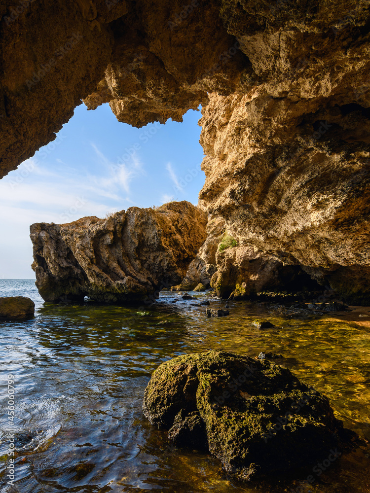 Naklejka premium A beautiful huge cave overlooking the rocks and the sea. Vertical landscape.