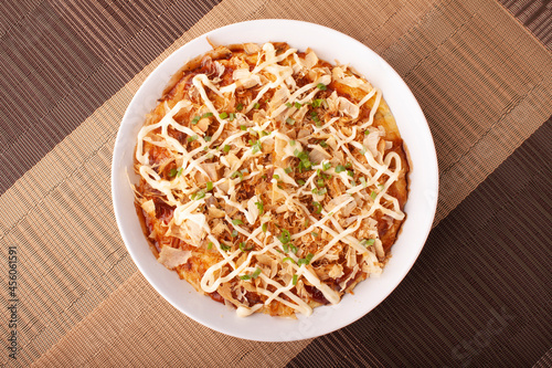 Фотография Delicious okonomiyaki on white plate at wooden table cloth from top view