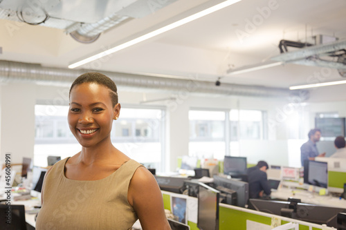 Portrait of smiling, confident businesswoman in open plan office