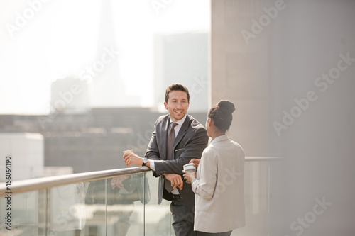 Businessman and businesswoman enjoying coffee on balcony, talking