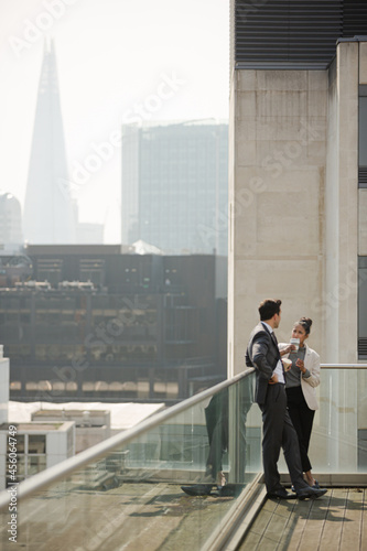 Businessman and businesswoman enjoying coffee on balcony, talking