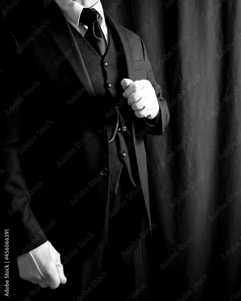 Portrait of Butler in Dark Suit and White Gloves Standing on Black Background. Copy Space for Service Industry and Professional Hospitality.