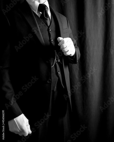 Portrait of Butler in Dark Suit and White Gloves Standing on Black Background. Copy Space for Service Industry and Professional Hospitality.