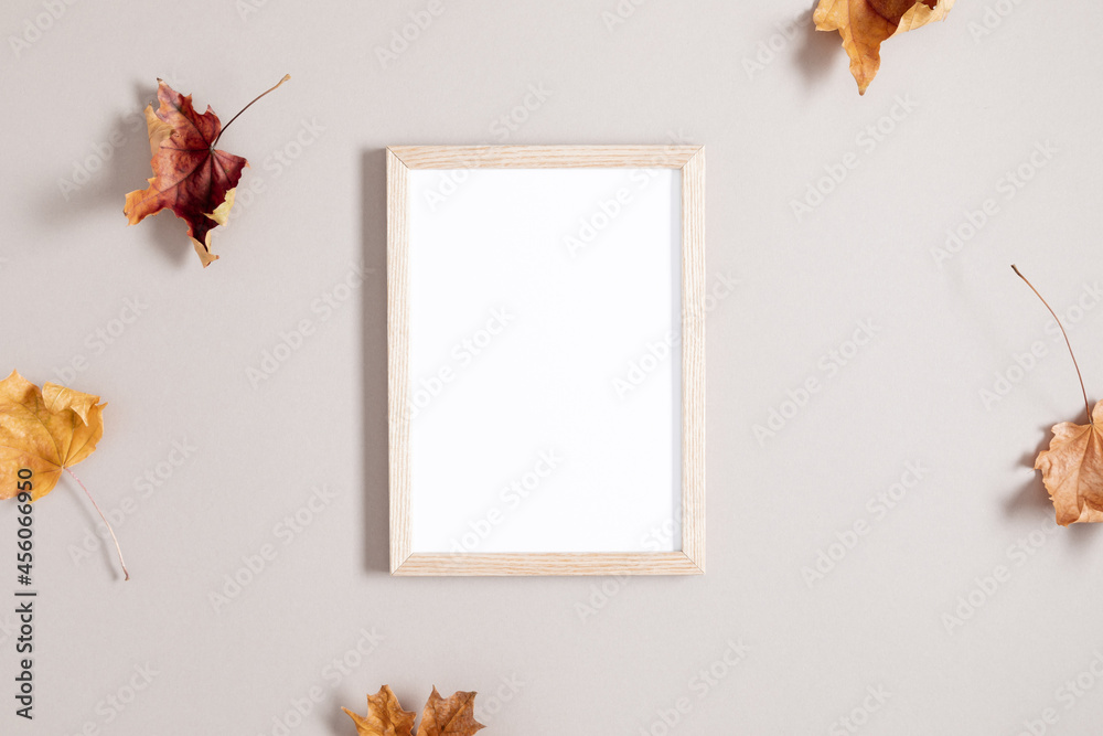 Wooden photo frame mockup and autumn leaves on gray background. Autumn composition. Flat lay, top view, copy space