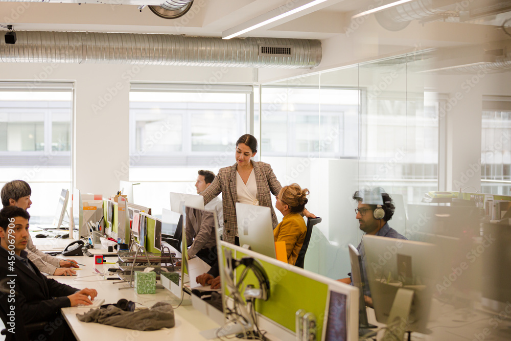 Business people talking at computer in open plan office Business people talking at computer in open plan office