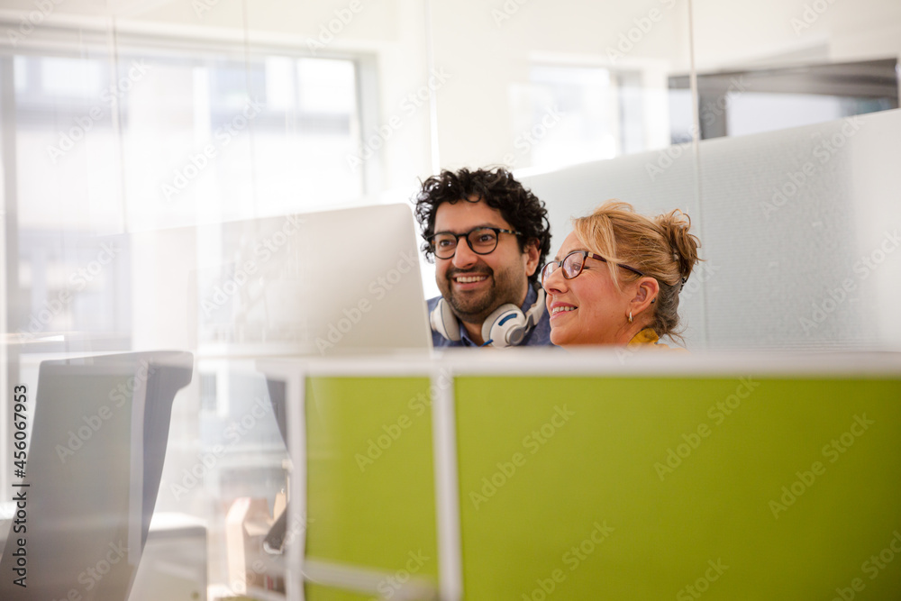 Business people talking at computer in open plan office Business people talking at computer in open plan office