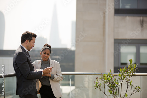 Businessman and businesswoman enjoying coffee on balcony, talking