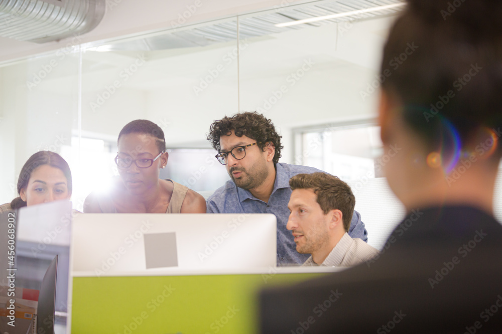 Business people brainstorming at computer in open plan office Business people brainstorming at computer in open plan office
