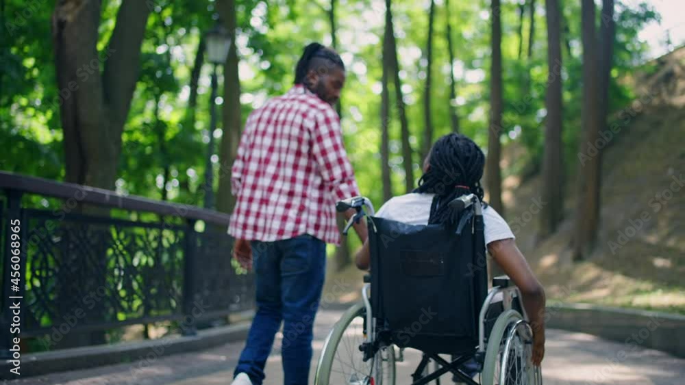 Man holding girlfriend in wheelchair by hand in park, recovery after surgery Man holding girlfriend in wheelchair by hand in park, recovery after surgery