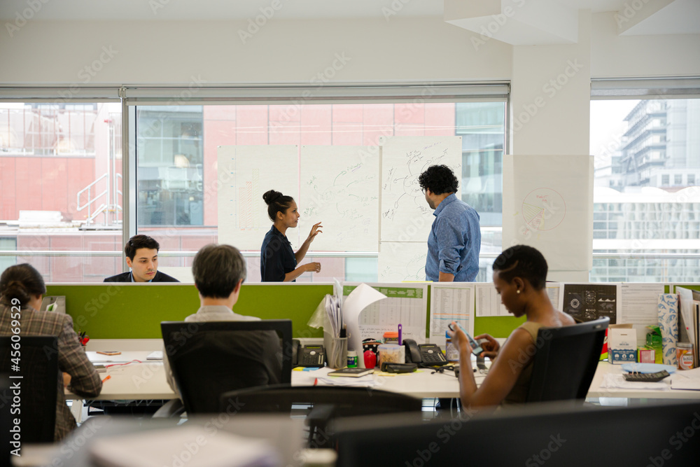 Business people discussing diagram sketches hanging on office window Business people discussing diagram sketches hanging on office window