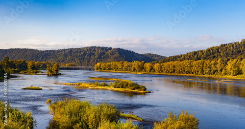Autumn landscape with hills, sky with clouds, forest, river with Islands and bridge