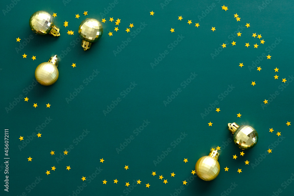 Vintage Christmas frame made of golden balls and confetti stars on green background. Flat lay, top view, overhead.