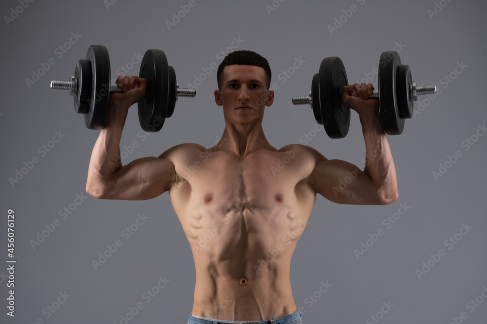 Strongman with muscular torso lift dumbbells in strong arms biceps triceps grey background, strength Strongman with muscular torso lift dumbbells in strong arms biceps triceps grey background, strength