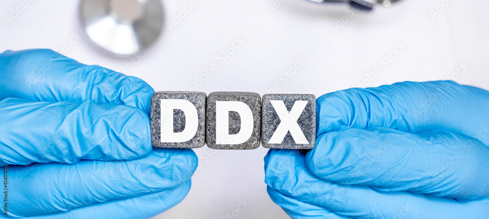 DDX Differential diagnosis - word from stone blocks with letters holding by a doctor's hands in medical protective gloves DDX Differential diagnosis - word from stone blocks with letters holding by a doctor's hands in medical protective gloves