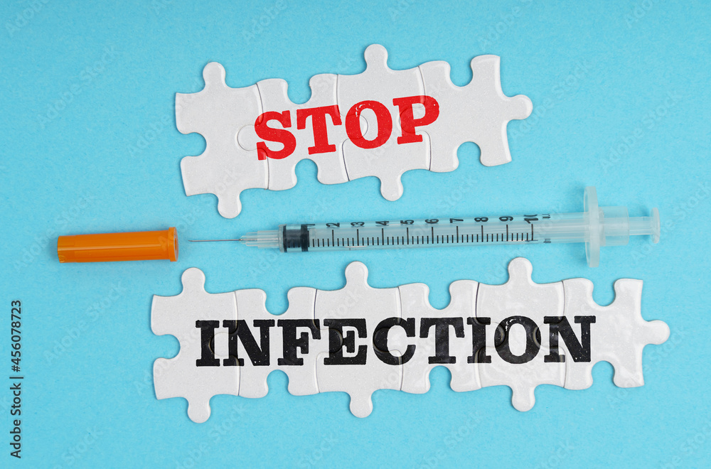 On a blue background, a syringe and puzzles with the inscription - STOP INFECTION On a blue background, a syringe and puzzles with the inscription - STOP INFECTION