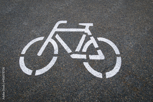Ein weißes Fahrrad ist als Symbol auf den grauen Asphalt  der Fahrbahn gemalt