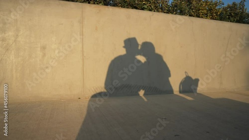 Shadows of young man and woman kissing in sunlight reflecting on wall. Silhouette of loving romantic couple in sunshine outdoors. Relationship and eternal love concept