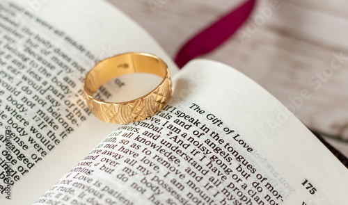 The gift of love from God and Jesus Christ. Christian biblical concept commitment of marriage relationship  1  Corinthians 13 Scripture verses. Closeup of a golden engagement ring on open Holy Bible.  photo