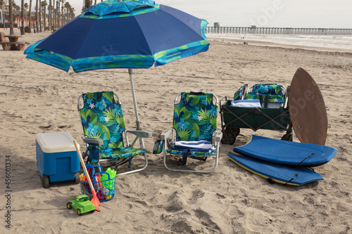 Fun at the beach with an ice chest, umbrella, chairs, toys, boogie boards, wagon, beach towels, and skimboard