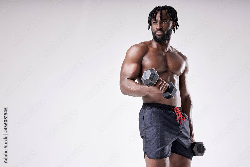 Fit afro american athlete exercising with dumbbell, training biceps, isolated in white studio background. Portrait of young powerful male with naked torso posing at camera. fitness concept Fit afro american athlete exercising with dumbbell, training biceps, isolated in white studio background. Portrait of young powerful male with naked torso posing at camera. fitness concept